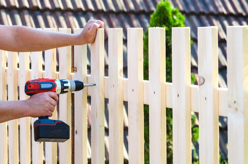 Image of man putting a fence together