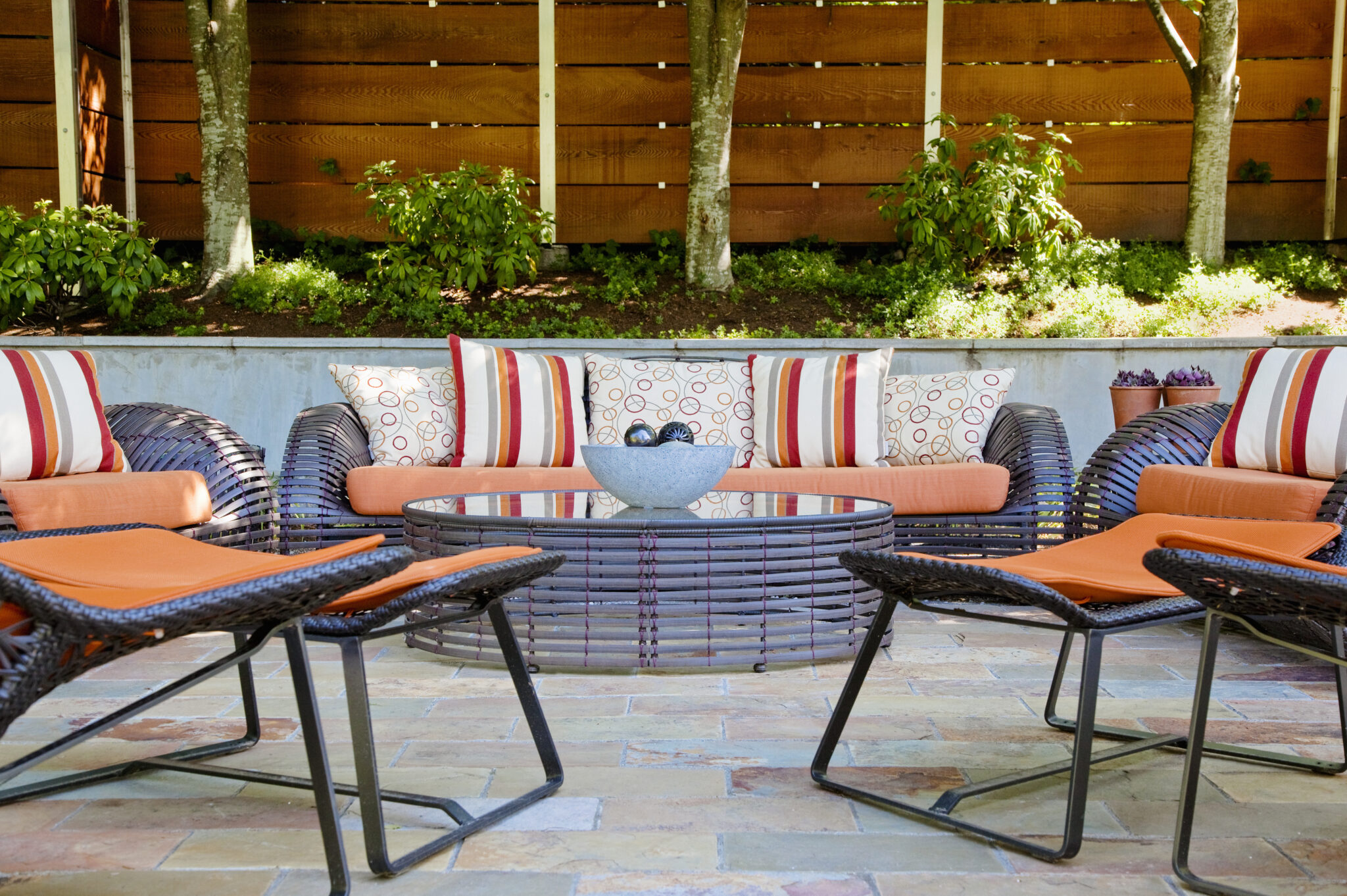 outdoor patio furniture surrounding a table in a lush backyard