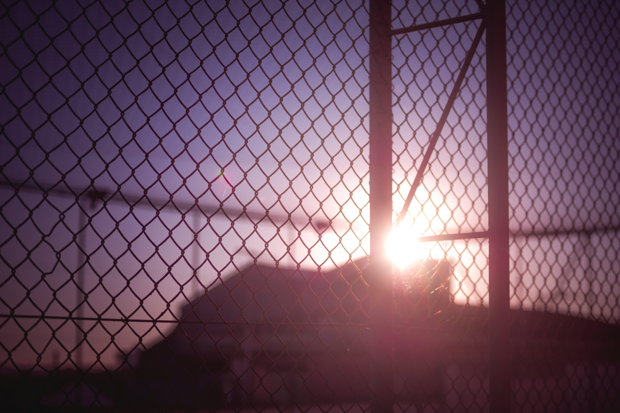 Sunset behind a wire fence.