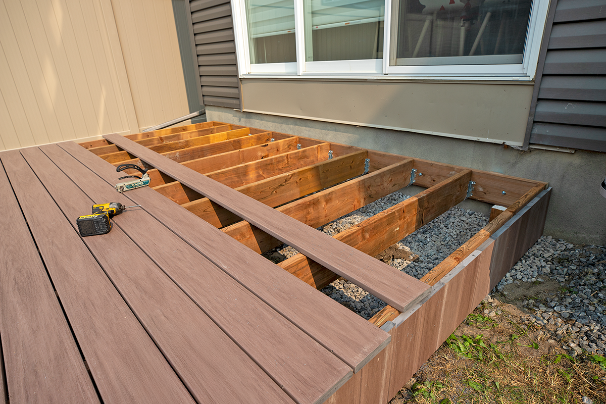 Contractor replacing deck boards during a deck re and re project using composite decking on an existing wooden frame.