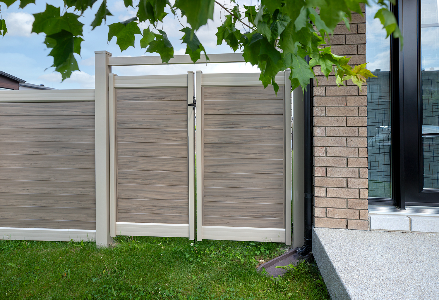 Modern composite privacy fence gate installed beside a brick home providing secure backyard access and clean contemporary design.