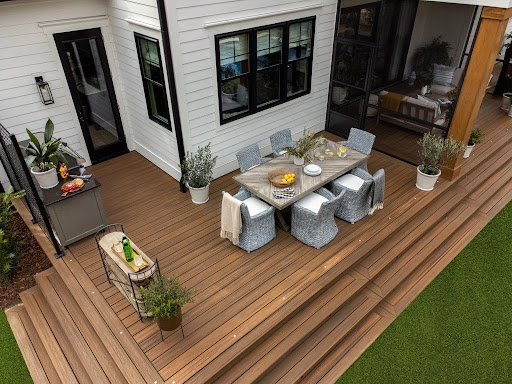 Large modern backyard deck with integrated outdoor dining area and multi-level wood decking attached to a contemporary home.