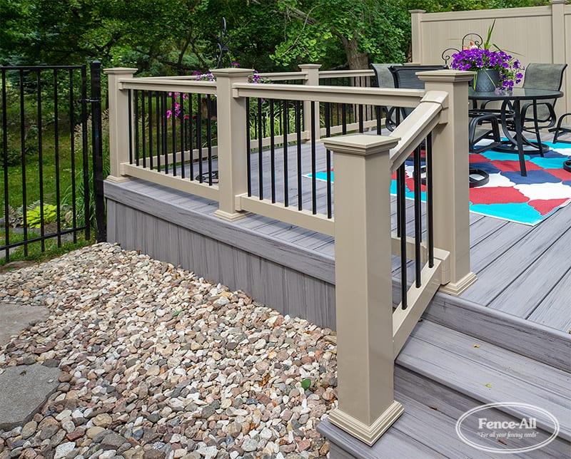 Vinyl and aluminum deck railing system installed on a cellular PVC backyard deck with stairs and landscaping.