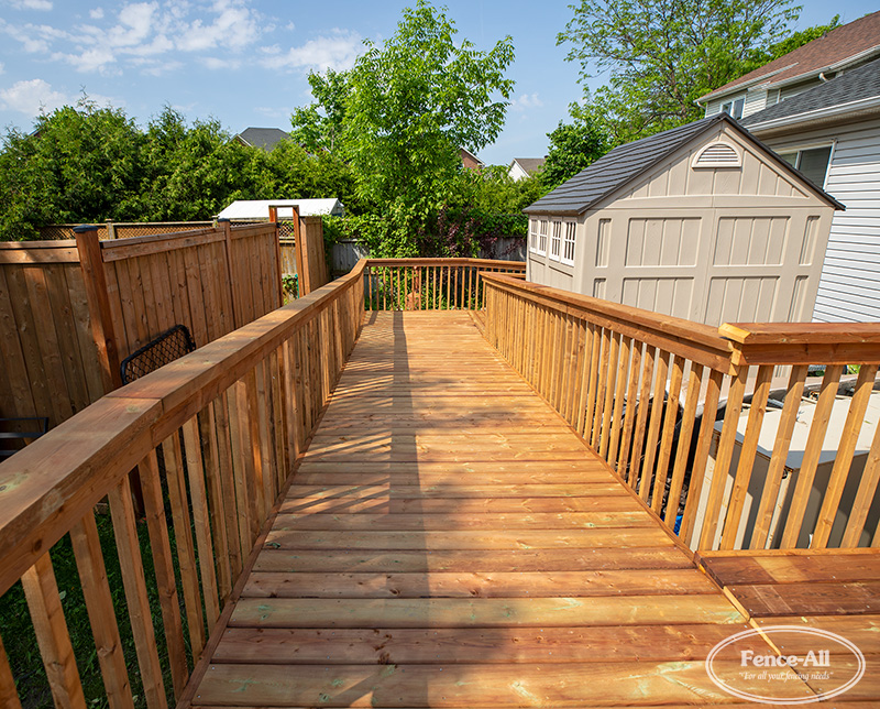 Custom wooden accessibility ramp with railings built beside a backyard shed in a residential Ottawa property.