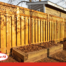 Wood privacy fence with lattice top in a residential backyard, featuring Fence-All branding.