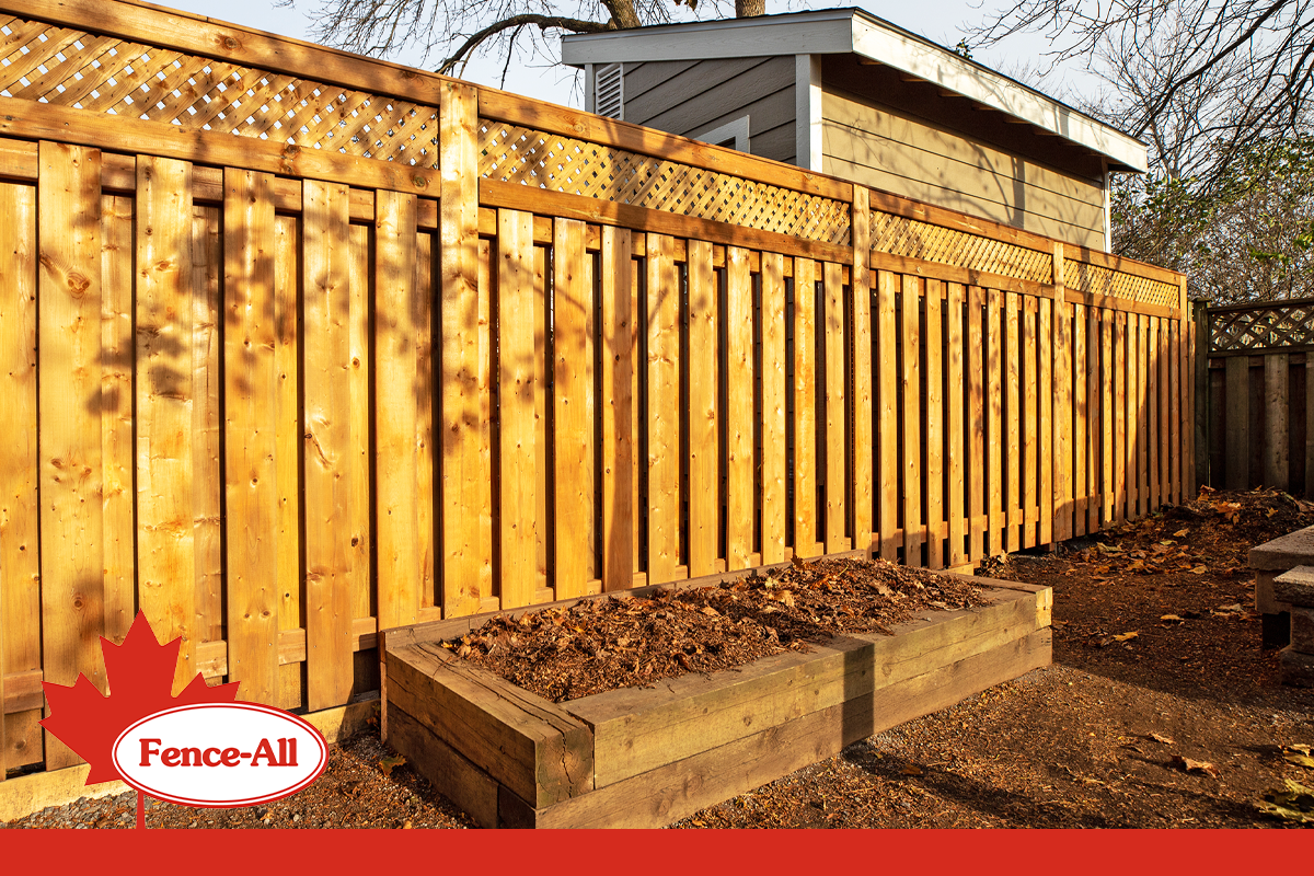 Wood privacy fence with lattice top in a residential backyard, featuring Fence-All branding.